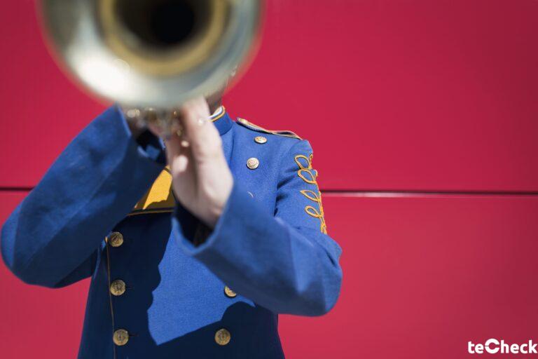 Señor con uniforme azul tocando una trompeta
